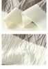 Close-up details of cream ribbed hem and cable-knit pattern