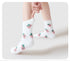 White fuzzy socks with cute pink strawberry pattern against white background