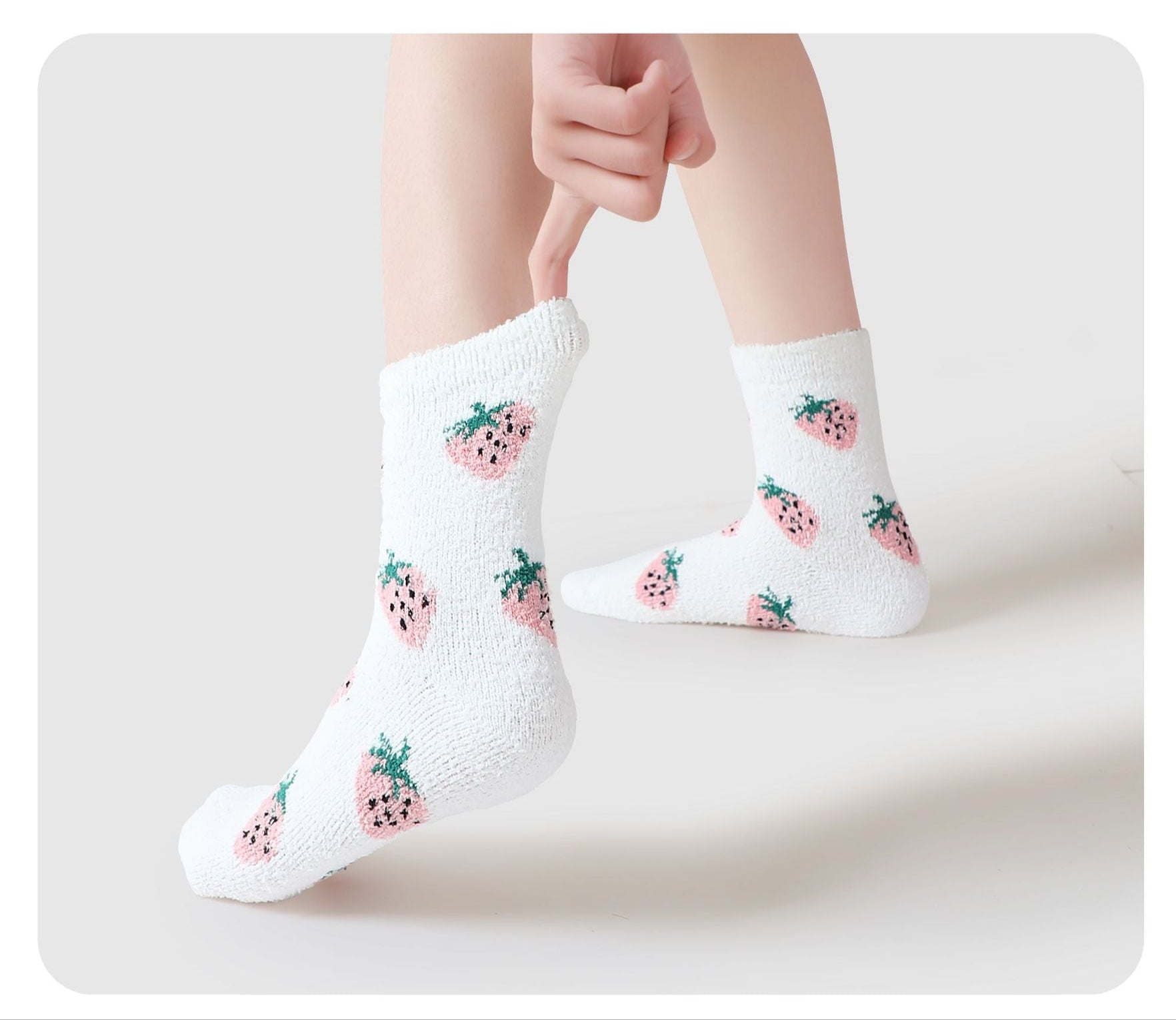 White fuzzy socks with cute pink strawberry pattern against white background