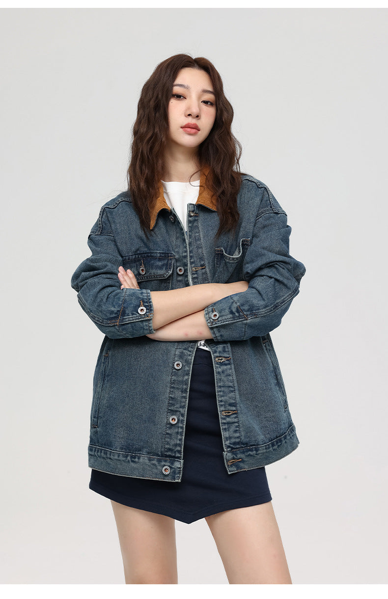 Woman with arms crossed wearing oversized blue denim jacket with brown collar over white tee and navy skirt