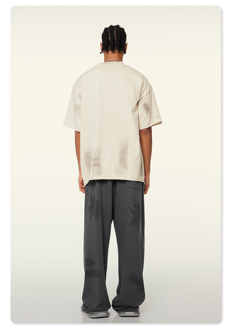 Back view of model wearing oversized white Beattube t-shirt and loose gray pants