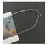 Full-length view of Cuban chain necklace laid flat on dark background, showcasing yellow smiley charm, planet charm, and crystal snake design