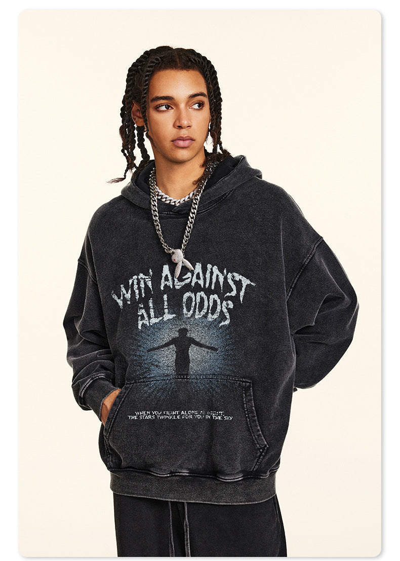 Model in black graphic hoodie with "Win Against All Odds" text, side profile in studio