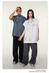 Two models in oversized t-shirts - gray and white - with wide-leg pants and silver sneakers against cream background