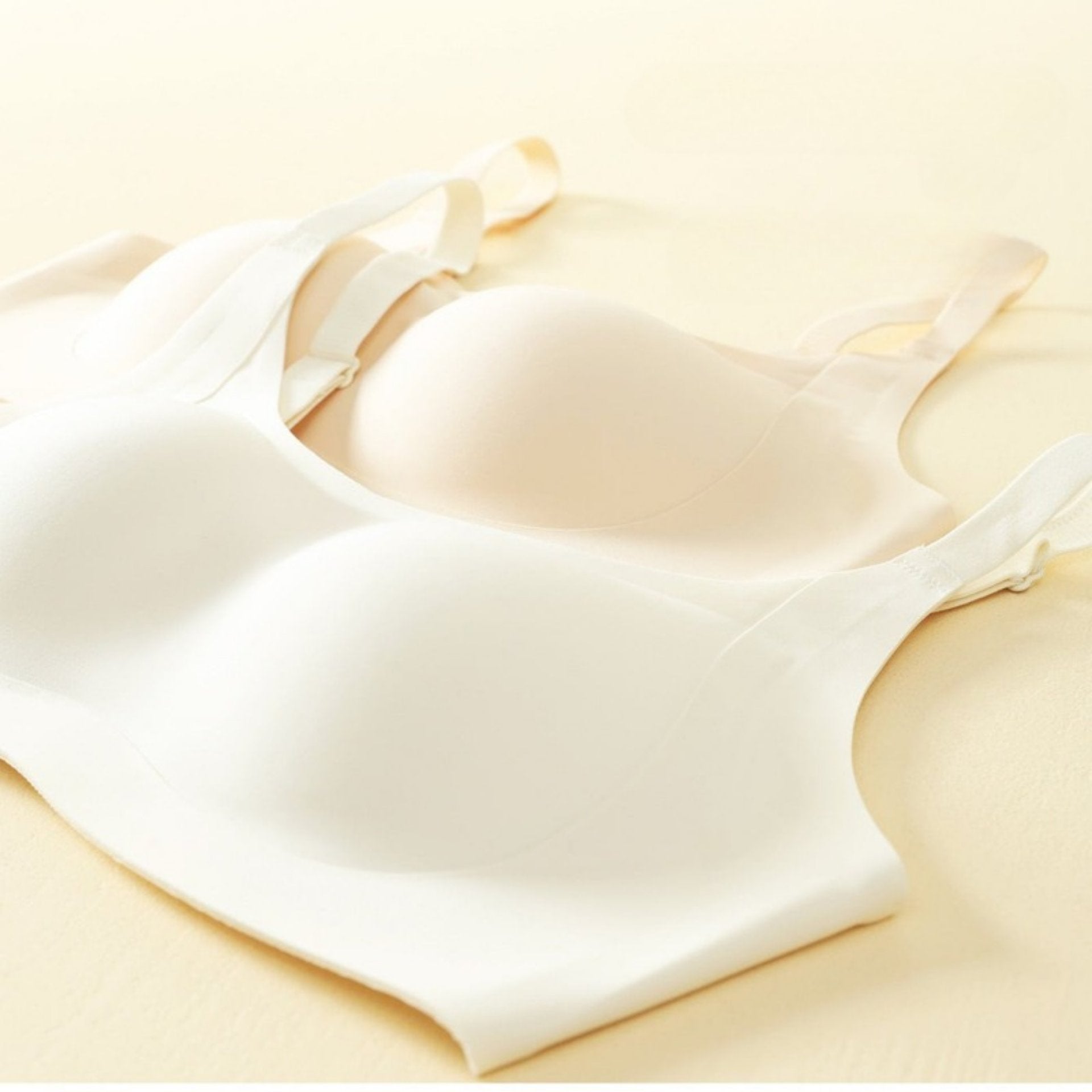 Close-up of seamless bras in cream and beige, highlighting smooth molded cups for natural shaping.