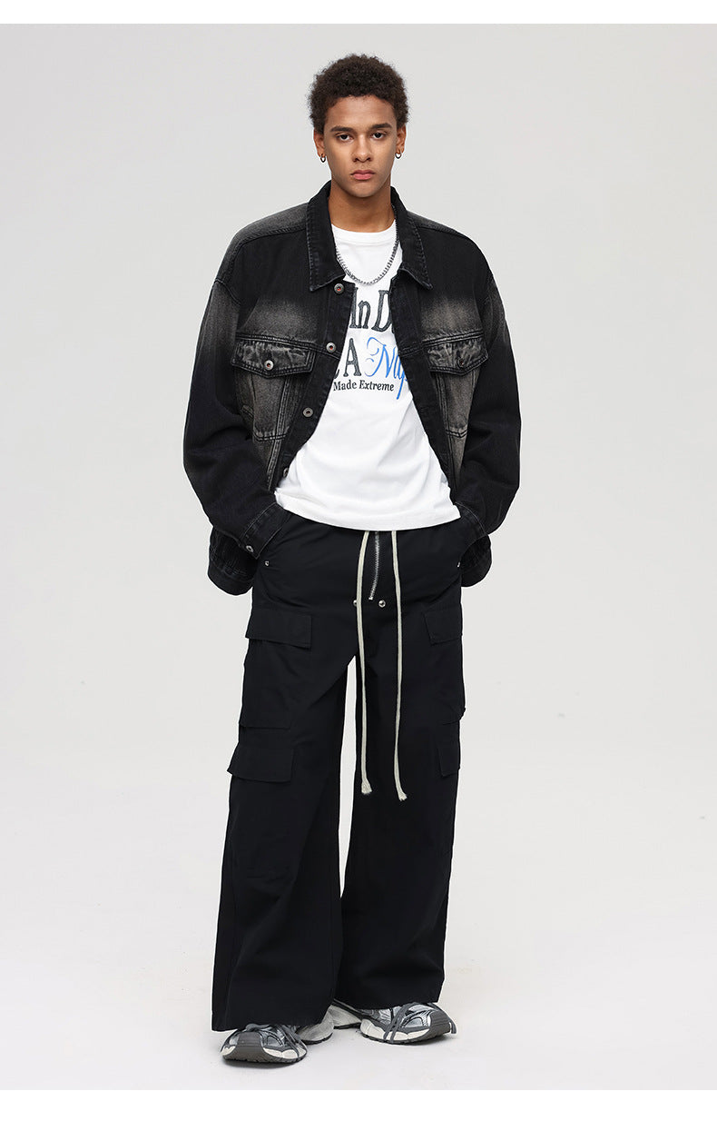 A full-body shot of a male model styling a black gradient denim jacket with wide-leg cargo pants and sneakers