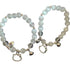 Two cat-themed bracelets with white opal beads, crystal cat charms, hearts and bells on white background