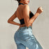Back view of black velvet halter top and fitted light wash jeans, showing open back design and silver chain detail