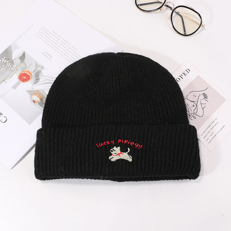 Black ribbed knit beanie featuring white puppy embroidery and red text