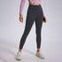 A model wearing black ankle-length leggings with pink long-sleeve crop top and white chunky sneakers, gray studio background