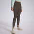 A model wearing dark brown athletic leggings with mint green crop top and cream colored chunky sneakers, gray backdrop