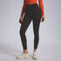 A model in black ankle-length leggings with orange long-sleeve crop top and white athletic sneakers, studio lighting
