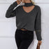 Woman in gray sweater with choker neckline and star-charm zippers, paired with black jeans and brown leather belt