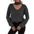 Woman in gray ribbed sweater with choker-style cutout, sleeve zippers, and dark jeans, holding brown leather purse