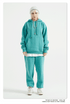 Model with platinum hair wearing a teal sweatsuit with oversized hoodie and matching joggers