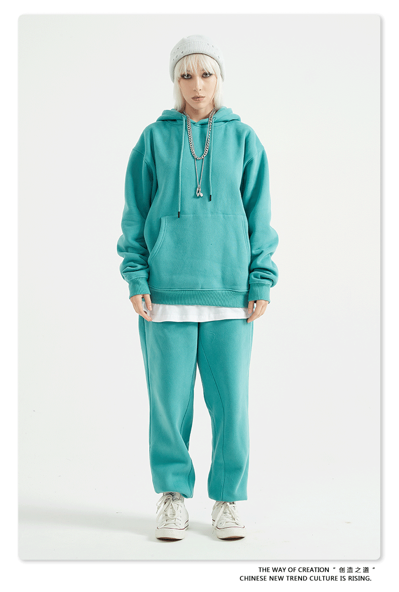 Model with platinum hair wearing a teal sweatsuit with oversized hoodie and matching joggers
