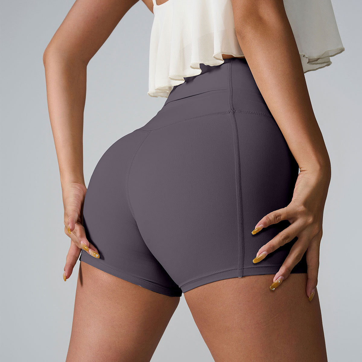 Close-up rear view of charcoal gray athletic shorts with cream ruffle top, displaying seamless design