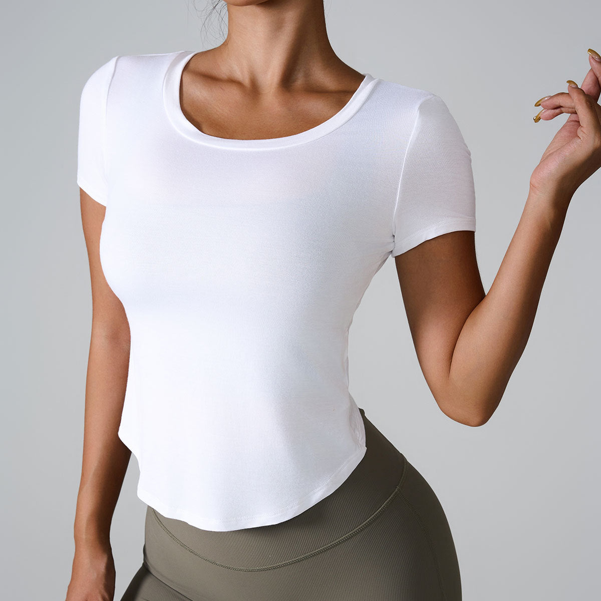 Woman wearing fitted white scoop neck t-shirt with olive green high-waisted leggings against gray background