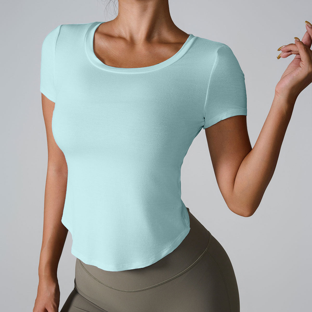 Woman in mint blue fitted scoop neck t-shirt with curved hem paired with olive green high-waisted leggings