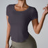 Woman wearing charcoal gray scoop neck t-shirt with curved hem paired with olive high-waisted leggings against gray backdrop