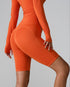 Orange compression bike shorts with high waist and seamless design, styled with matching long sleeve top and chunky sneakers