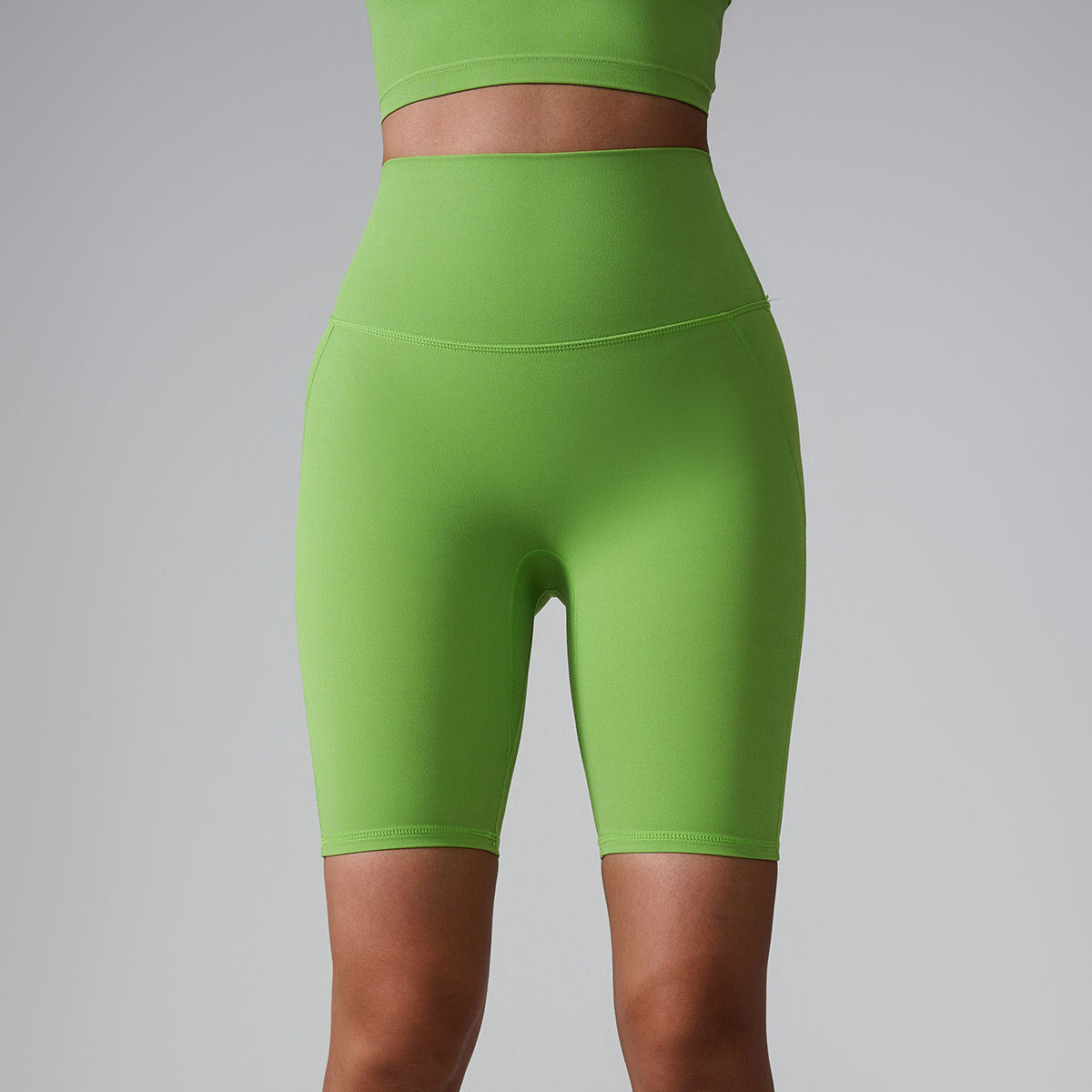 Lime green high-waisted athletic shorts with matching sports bra, showing compression fit