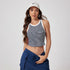 A woman in white Nike cap and hoop earrings wearing black and white striped crop top with navy drawstring pants against white backdrop