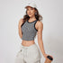 A woman wearing a black and white striped crop tank top and cream cargo pants poses with coffee cup on white background, styled with Nike cap