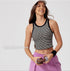 A smiling woman in white Nike cap wearing striped crop tank with white trim paired with lilac cargo pants, shown against clean background