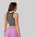 A back view of woman wearing black and white striped crop top with purple cargo pants against neutral gray background showing fitted silhouette