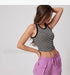 A woman posing with hand on hip wearing black and white striped fitted crop top with lilac cargo pants against minimal white background