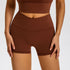 Chocolate brown athletic shorts with high-rise crossover waistband and seamless compression fabric against white backdrop