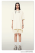 Woman with straight black hair wearing cream oversized T-shirt and shorts with textured white sneakers