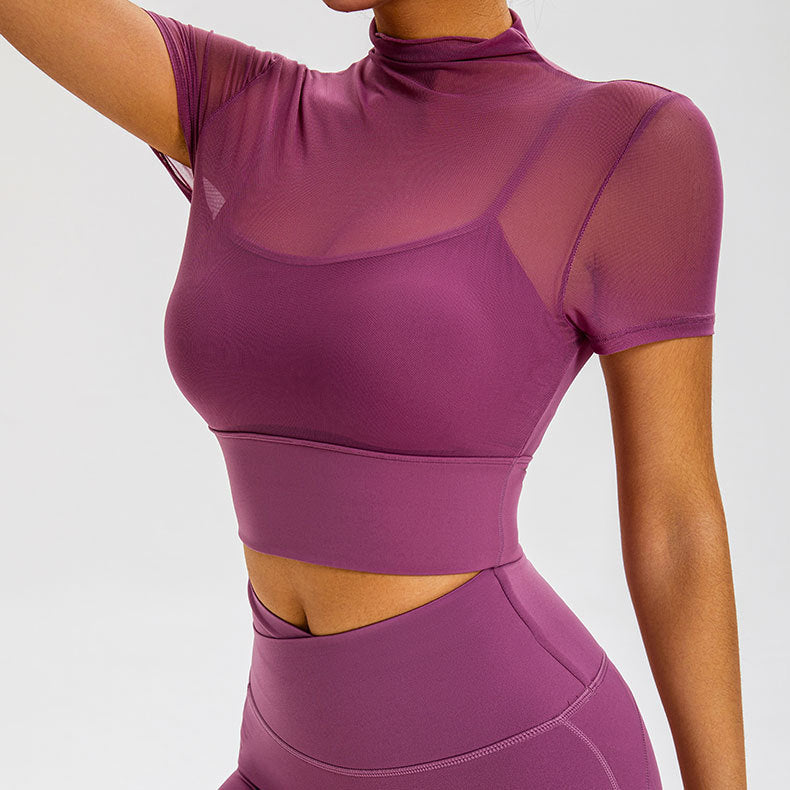 Model in purple workout set with sheer mock neck top over sports bra and matching high-waist leggings