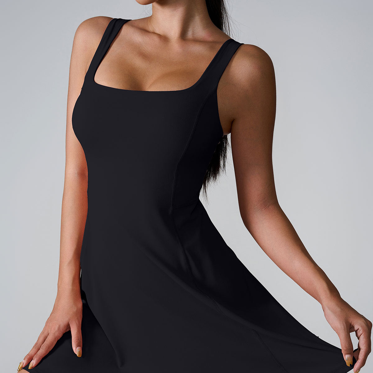 A model wearing classic black square-neck sleeveless dress with contoured seams against minimalist gray background