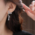 Side view of silver bow earring with crystal embellishments worn on ear, showing elegant profile against dark hair