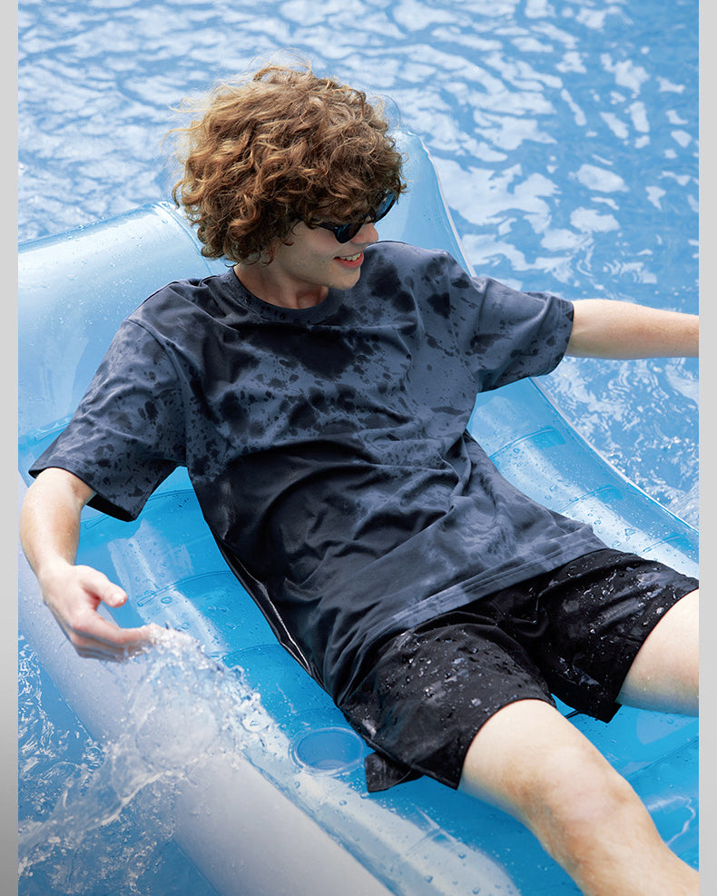 Male model in black moisture-wicking tee relaxing poolside