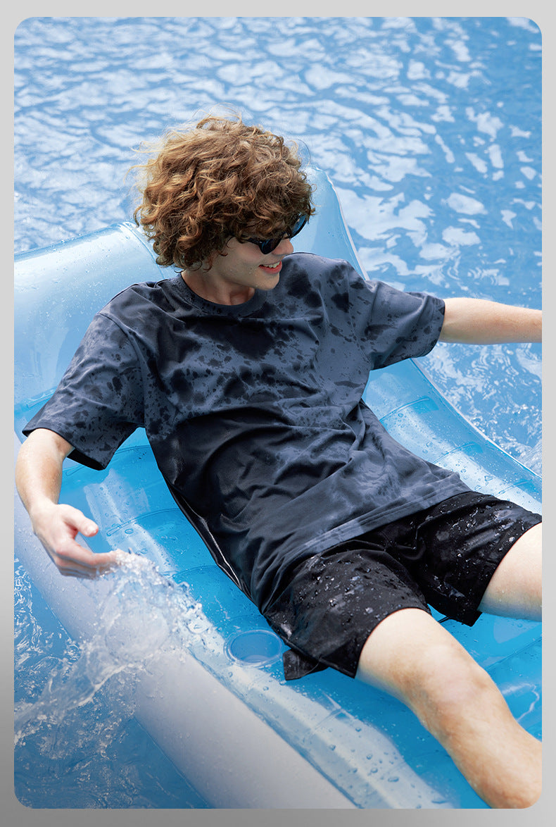 Male model in black moisture-wicking tee relaxing poolside