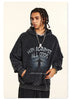 Model facing forward in black graphic hoodie, wearing chain necklace and braided hair