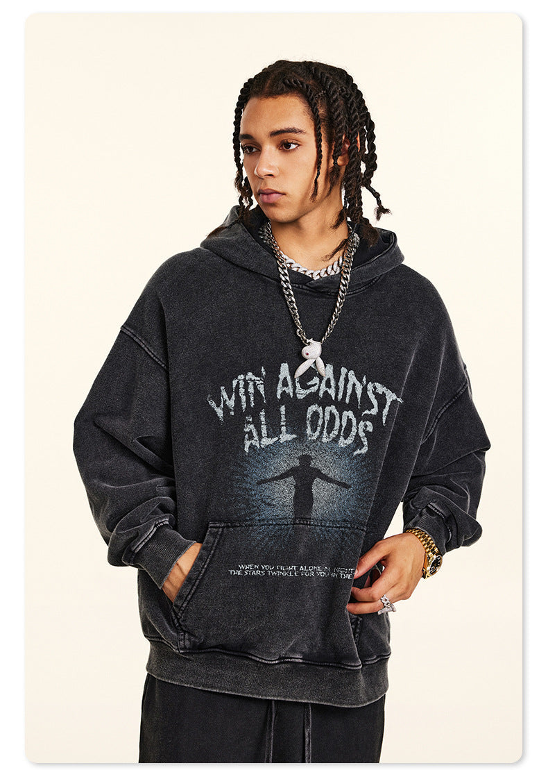 Model facing forward in black graphic hoodie, wearing chain necklace and braided hair