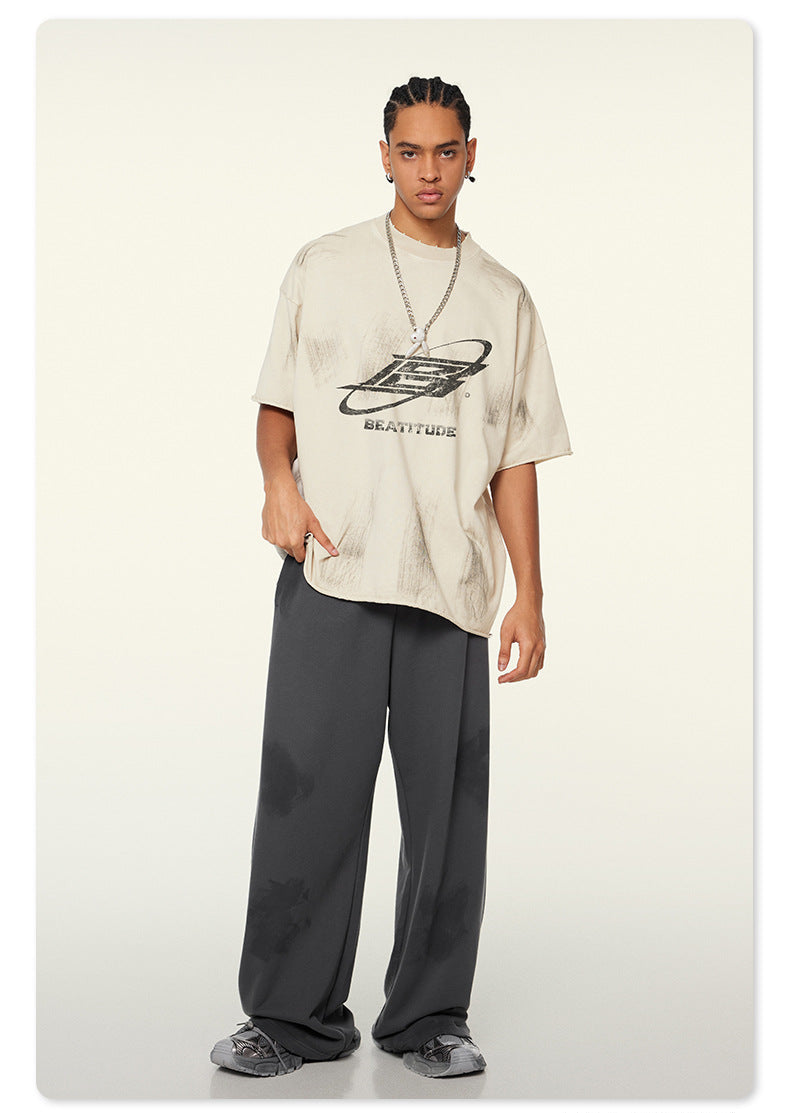 Front view of model in distressed white Beattube t-shirt and wide charcoal pants