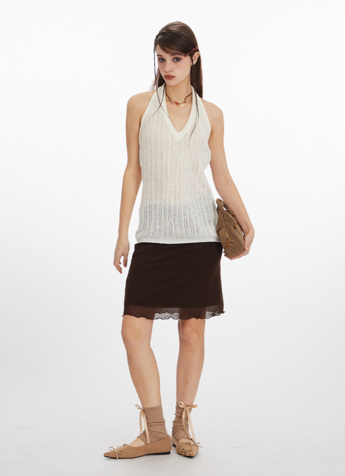Full body shot of model wearing white tank top and dark brown mesh skirt