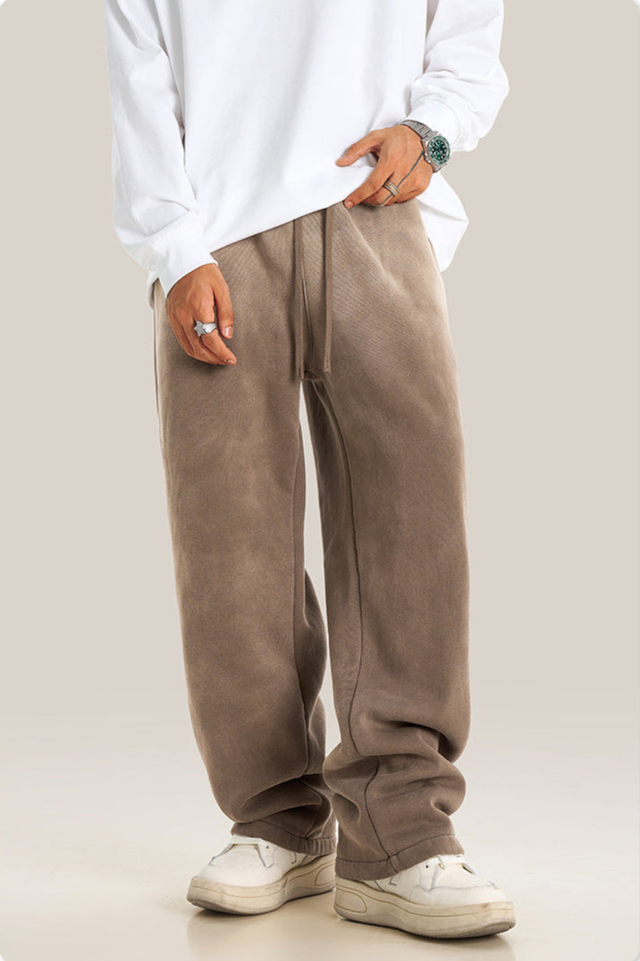 Person wearing taupe wide-leg sweatpants with white sweater, silver watch and white sneakers, showing relaxed streetwear styling