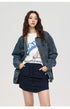 Woman in denim jacket with brown collar over graphic tee showing "LIFE IN THE FIRE" text and navy mini skirt