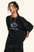 Close-up portrait of model wearing black Backstairs tee with silver necklace against white background