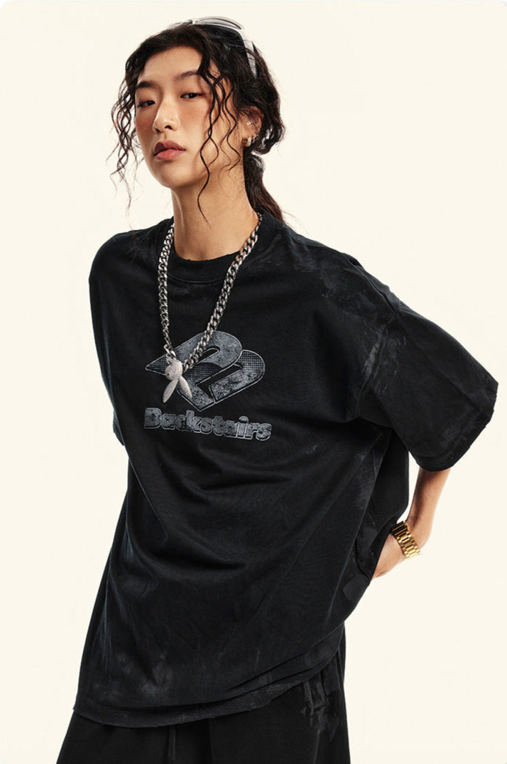 Close-up portrait of model wearing black Backstairs tee with silver necklace against white background
