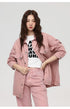A woman with wavy hair modeling oversized pink denim jacket and matching jeans with white graphic tee