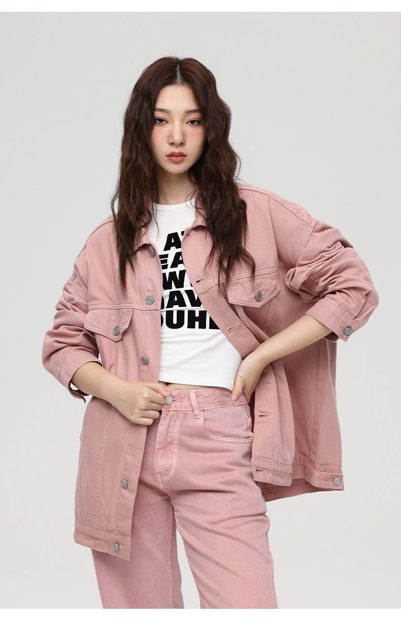 A woman with wavy hair modeling oversized pink denim jacket and matching jeans with white graphic tee
