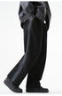 Side view of black wide-leg drawstring pants worn with a gray jacket and black sneakers