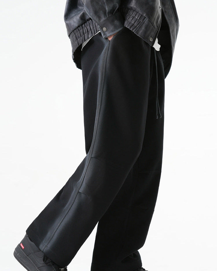 Side view of black wide-leg drawstring pants worn with a gray jacket and black sneakers